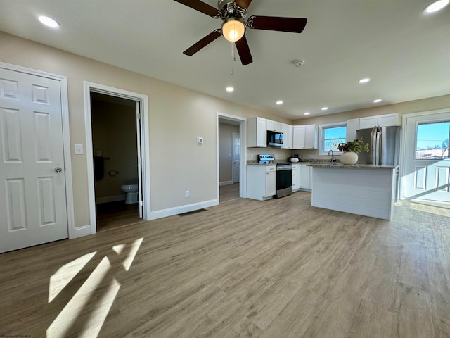 kitchen with stainless steel appliances, white cabinets, sink, ceiling fan, and light hardwood / wood-style flooring