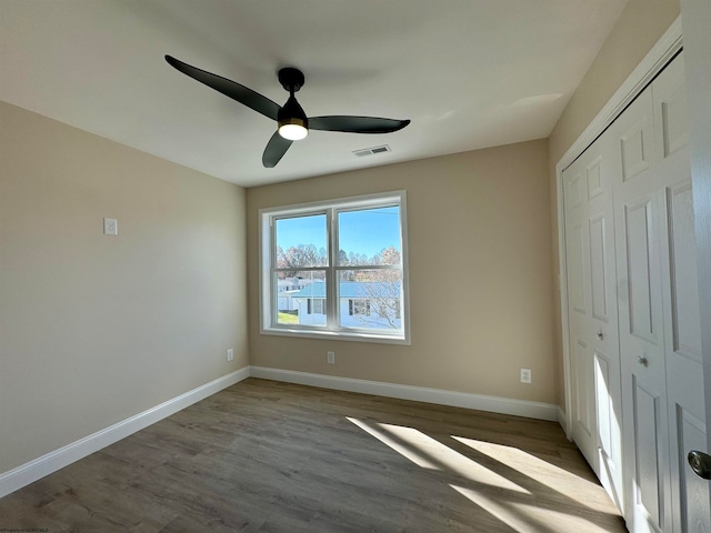 unfurnished bedroom featuring a closet, wood-type flooring, and ceiling fan