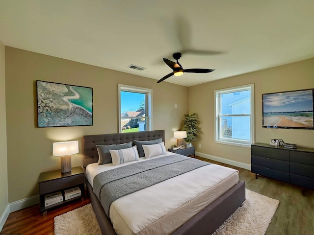 bedroom with ceiling fan, multiple windows, and dark hardwood / wood-style flooring