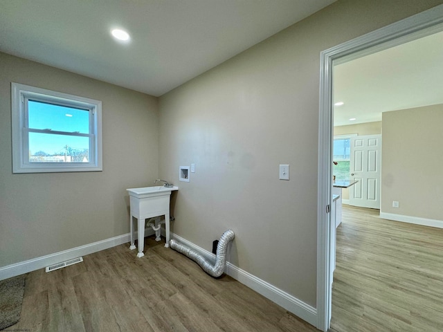 washroom with washer hookup and light hardwood / wood-style flooring