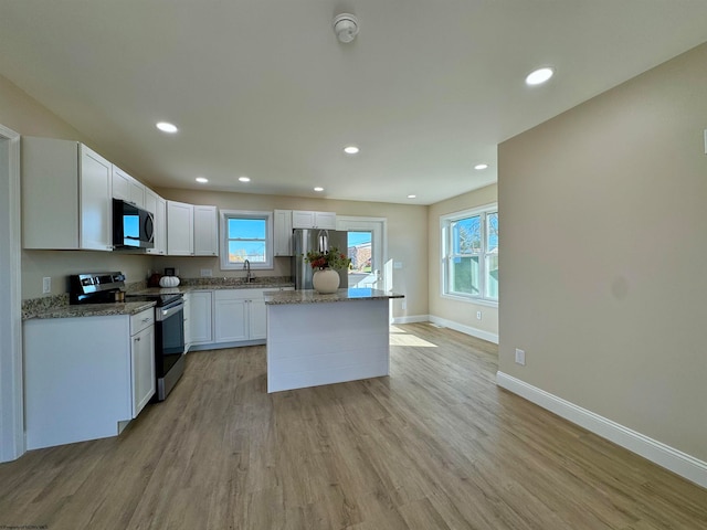 kitchen with white cabinetry, light wood-type flooring, stainless steel appliances, and a wealth of natural light