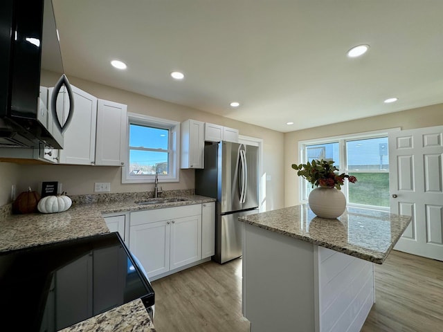 kitchen featuring white cabinets, appliances with stainless steel finishes, sink, and a center island