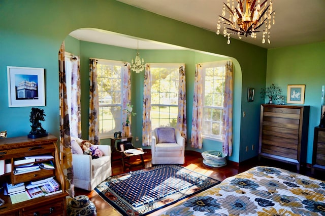 bedroom with multiple windows, an inviting chandelier, and hardwood / wood-style flooring