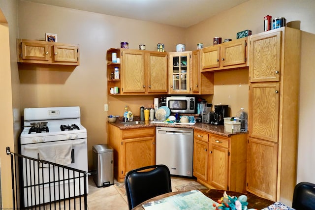 kitchen featuring dark stone countertops, light tile patterned floors, and stainless steel appliances