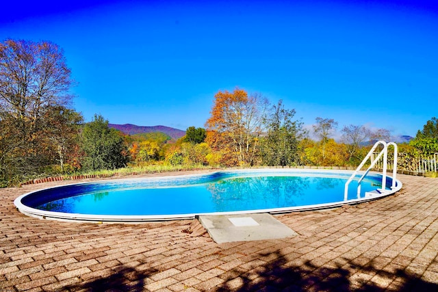 view of swimming pool featuring a patio area and a mountain view