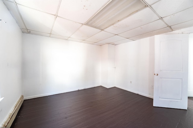 spare room with baseboard heating, a paneled ceiling, and dark hardwood / wood-style floors