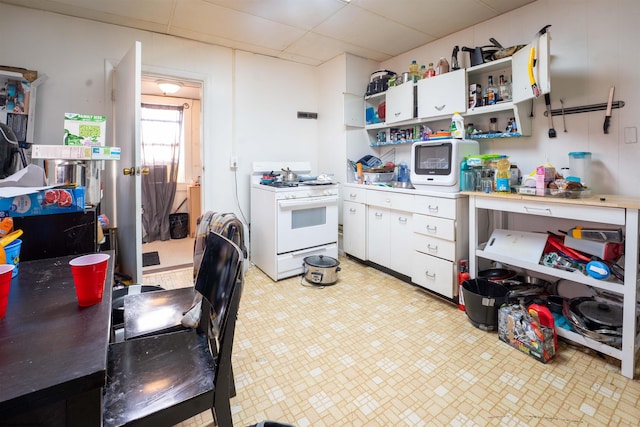 kitchen with white range with gas stovetop and white cabinets