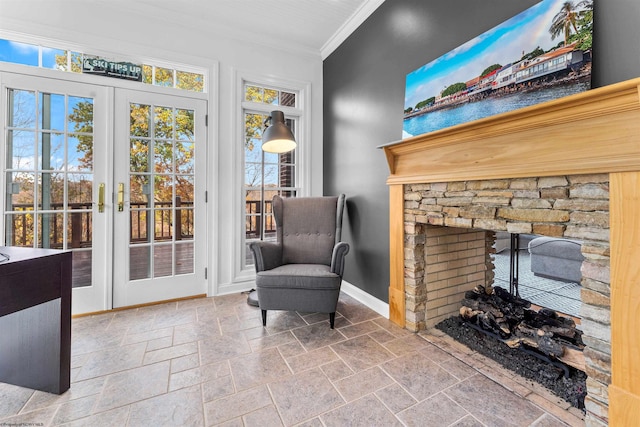 living area featuring a stone fireplace, french doors, and ornamental molding