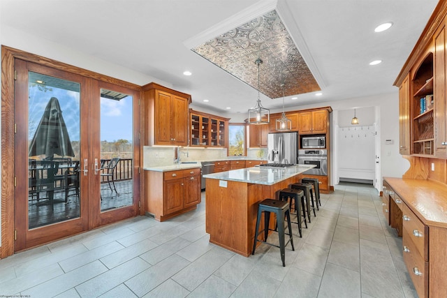 kitchen with appliances with stainless steel finishes, a kitchen bar, backsplash, decorative light fixtures, and a center island