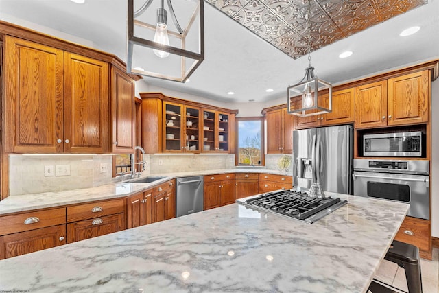 kitchen featuring sink, light stone counters, appliances with stainless steel finishes, a kitchen breakfast bar, and hanging light fixtures