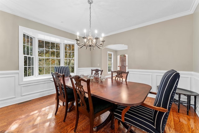 dining room with hardwood / wood-style flooring, an inviting chandelier, and ornamental molding