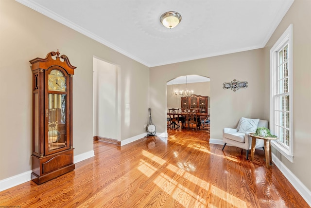 living area with ornamental molding, hardwood / wood-style floors, and a chandelier