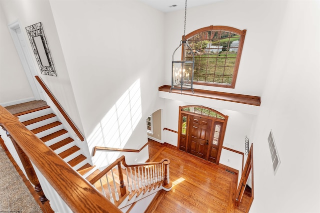 foyer featuring wood-type flooring, a chandelier, and a high ceiling