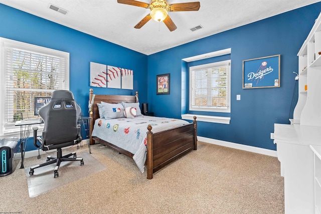 bedroom with ceiling fan, multiple windows, a textured ceiling, and light colored carpet