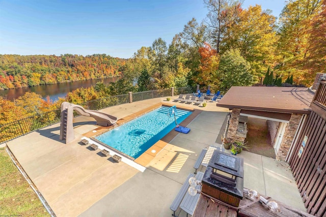 view of pool featuring a water view, a water slide, and a patio area