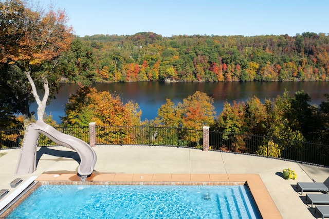 view of pool with a patio, a water view, and a water slide