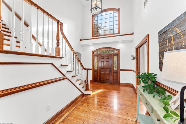 foyer featuring a high ceiling, a chandelier, and light hardwood / wood-style flooring