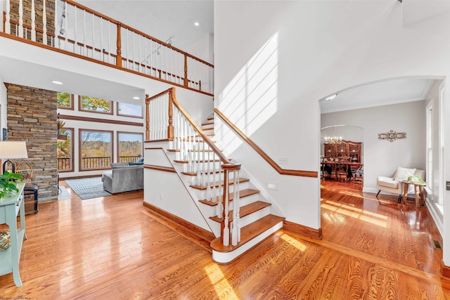 staircase featuring a high ceiling, crown molding, and hardwood / wood-style flooring