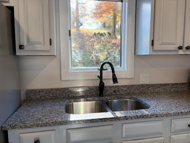 kitchen featuring white cabinets, sink, and dark stone countertops