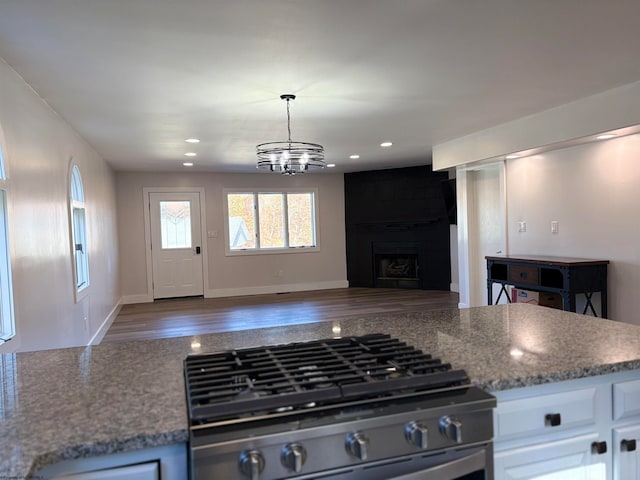 kitchen featuring dark hardwood / wood-style flooring, white cabinets, a notable chandelier, stainless steel range, and stone countertops