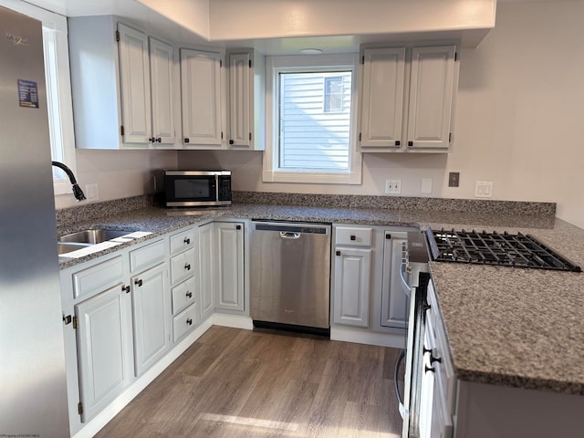 kitchen with white cabinets, appliances with stainless steel finishes, sink, and dark hardwood / wood-style flooring