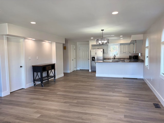 kitchen with kitchen peninsula, sink, hardwood / wood-style flooring, and stainless steel appliances