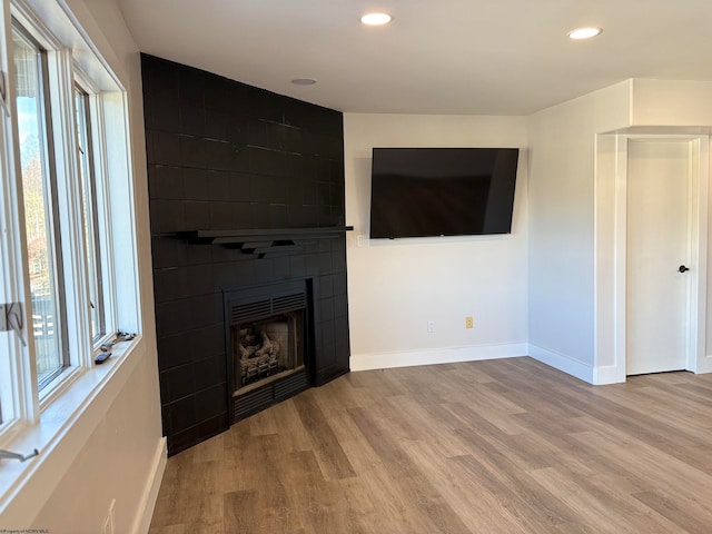 unfurnished living room featuring a tile fireplace and light hardwood / wood-style flooring