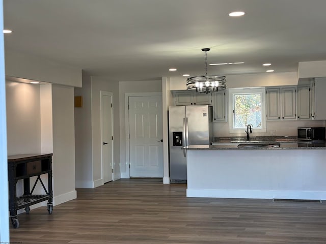 kitchen featuring kitchen peninsula, stainless steel appliances, hanging light fixtures, and dark hardwood / wood-style flooring