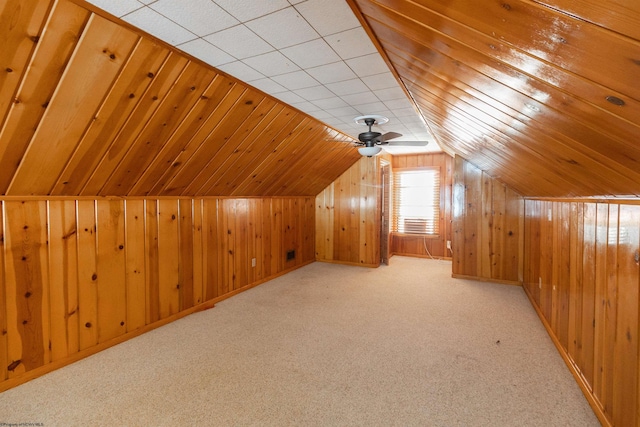 bonus room featuring wood walls, ceiling fan, and light colored carpet