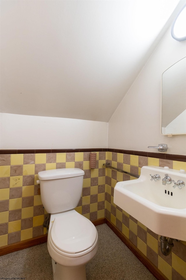 bathroom with toilet, tile walls, and vaulted ceiling