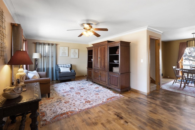 living room with ornamental molding, dark wood-type flooring, and ceiling fan