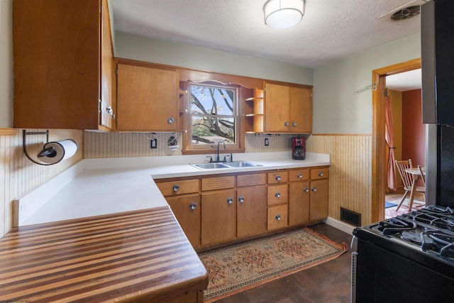 kitchen with a textured ceiling, sink, black range with gas stovetop, and dark hardwood / wood-style flooring