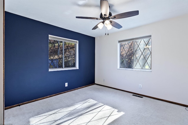 spare room featuring a wealth of natural light, ceiling fan, and carpet flooring