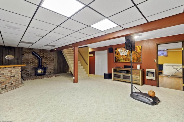 basement with heating unit, carpet flooring, a wood stove, and a drop ceiling