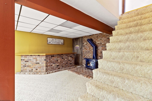 basement with a wood stove and carpet flooring