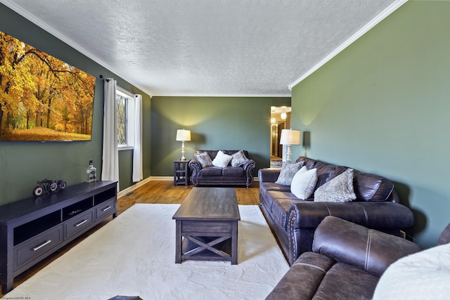 living room with light hardwood / wood-style floors, a textured ceiling, and ornamental molding