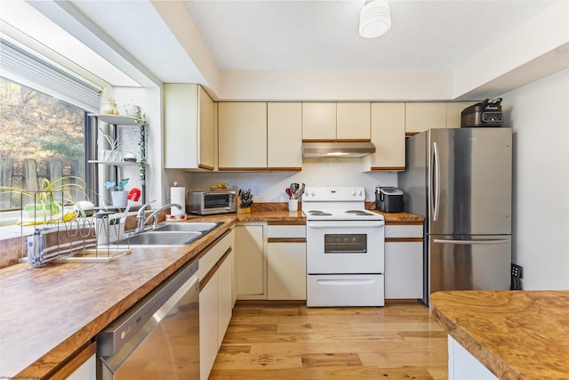 kitchen featuring cream cabinetry, stainless steel appliances, light hardwood / wood-style flooring, and sink