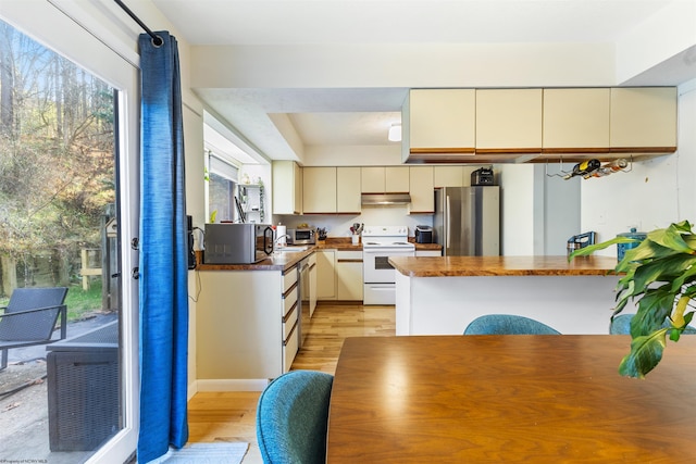 kitchen featuring kitchen peninsula, cream cabinetry, light hardwood / wood-style floors, and stainless steel appliances