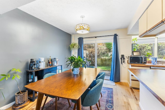 dining space with a textured ceiling and light wood-type flooring