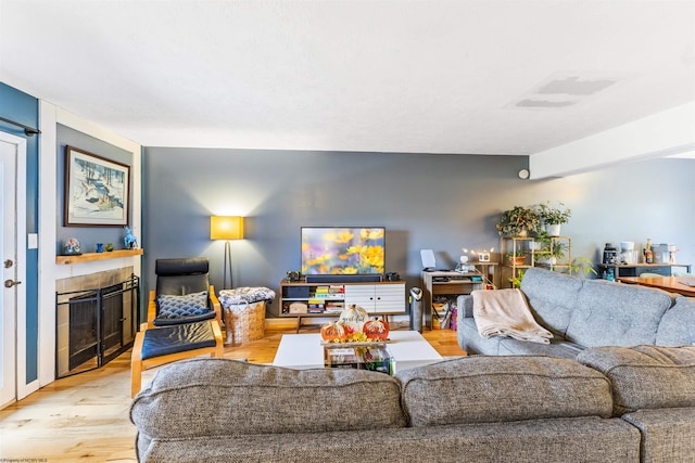 living room with a tile fireplace and light hardwood / wood-style floors