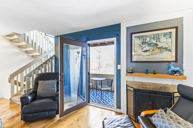 living area with wood-type flooring and a tile fireplace