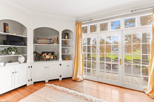 doorway to outside featuring built in features, light hardwood / wood-style floors, and ornamental molding