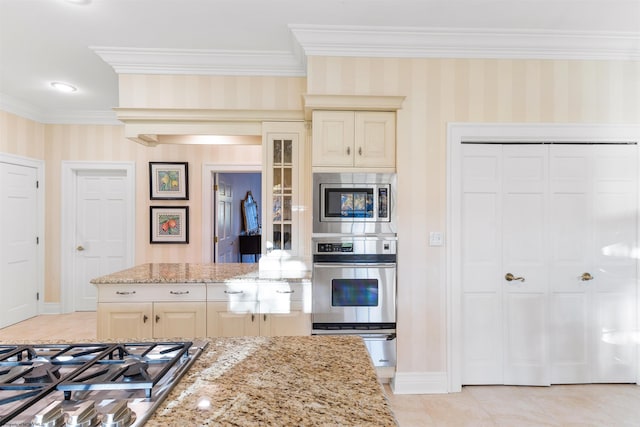 kitchen featuring ornamental molding, cream cabinets, light tile patterned floors, light stone countertops, and stainless steel appliances