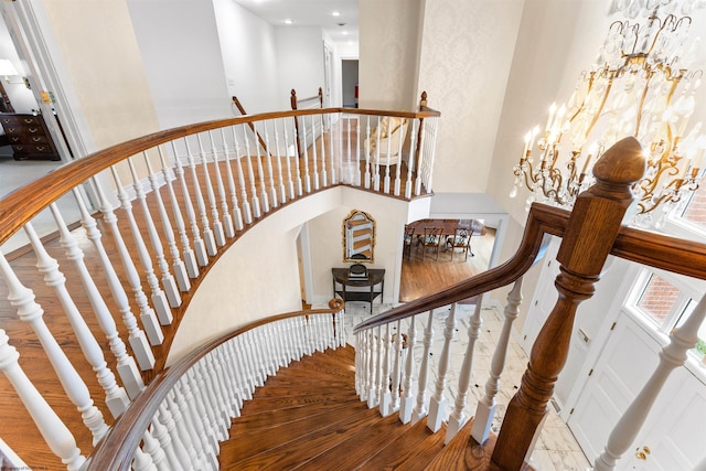 stairs featuring a chandelier, hardwood / wood-style floors, and a high ceiling