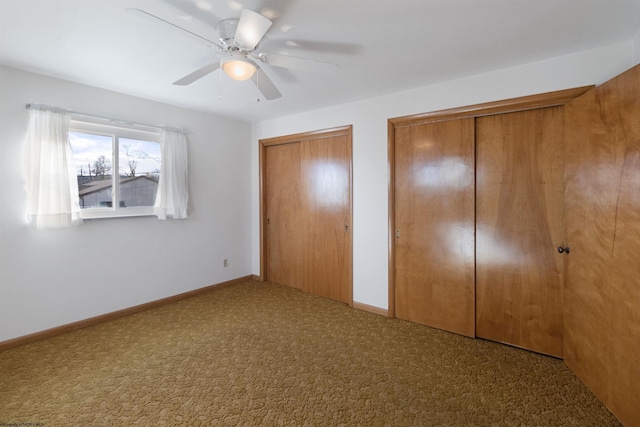 unfurnished bedroom with carpet flooring, multiple closets, and ceiling fan