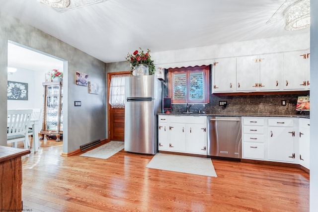 kitchen featuring sink, appliances with stainless steel finishes, dark stone counters, white cabinets, and light wood-type flooring