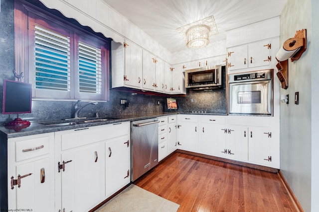 kitchen with white cabinetry, sink, stainless steel appliances, tasteful backsplash, and dark hardwood / wood-style flooring