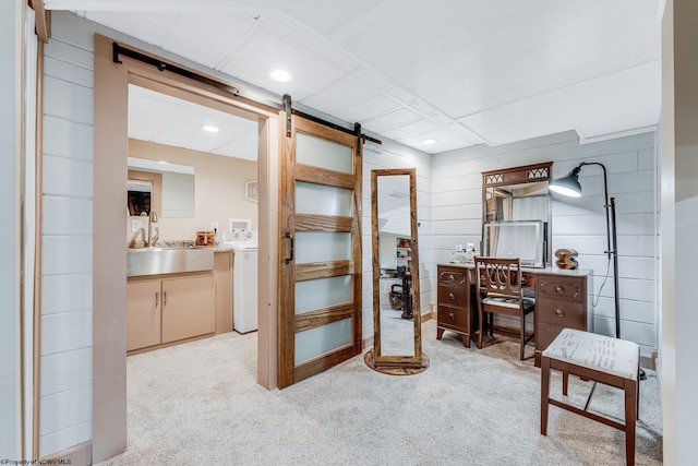 carpeted office featuring a barn door, sink, and washer / dryer