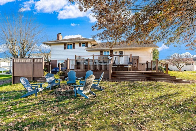 rear view of property featuring an outdoor fire pit, a yard, and a wooden deck