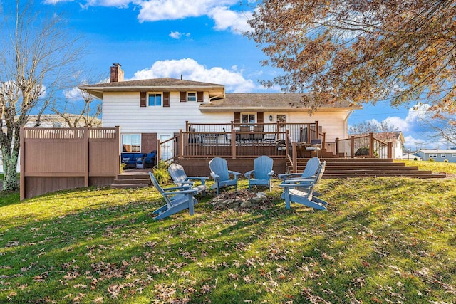 back of house with a yard, a deck, and an outdoor fire pit